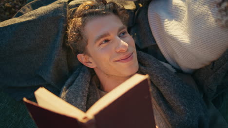 tranquil man lying woman knees enjoying picnic closeup. boyfriend reading book