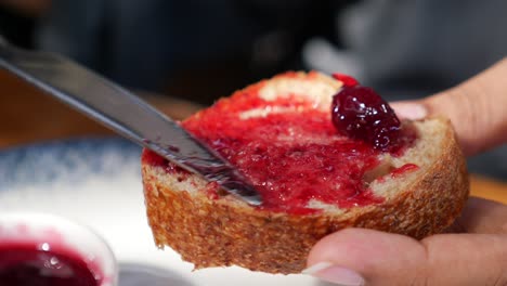 person eating a slice of bread with cherry jam