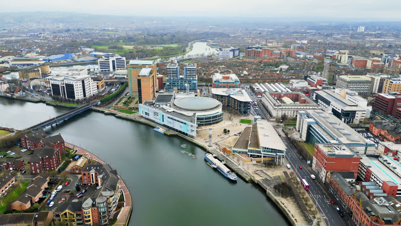 Aerial drone view of cars driving over the buildings surrounding River Lagan