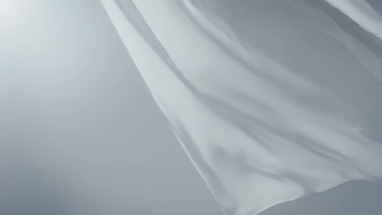 White Fabric Waving in the Wind Against a Grey Background