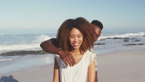 hombre afroamericano sorprendiendo a su esposa en la playa