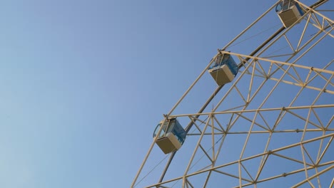 rueda gigante contra el cielo, levántate lentamente a la parte superior de la cabina para ver el parque de atracciones o la feria desde una altura. diseño de rueda gigante con cabinas blancas y ventanas azules