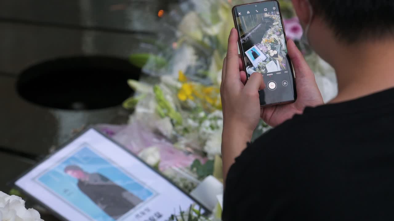 A mourner takes a photo of flower bouquets outside the British Consulate General as a tribute after the passing of the longest-serving monarch Queen Elizabeth II.