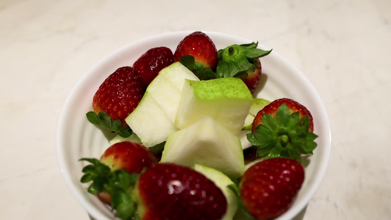 A bowl of strawberries and pear slices