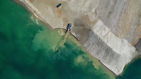 aerial top down view of an excavator moving crushed stone into the water in hungary