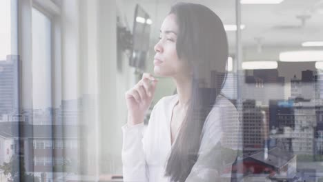 Animation-of-cityscape-over-biracial-businesswoman-in-office