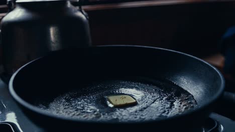 a person is melting butter in a pan on the stove in a rustic kitchen in reinsjøen, åfjord, trøndelag, norway - close up