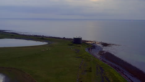 vast aerial view of aughinish martello tower at twilight. drone moves forward to the gun tower