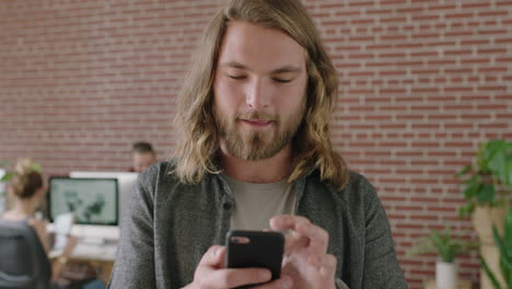 portrait of young caucasian man in office internet cafe texting browsing using smartphone mobile app enjoying networking in business workspace