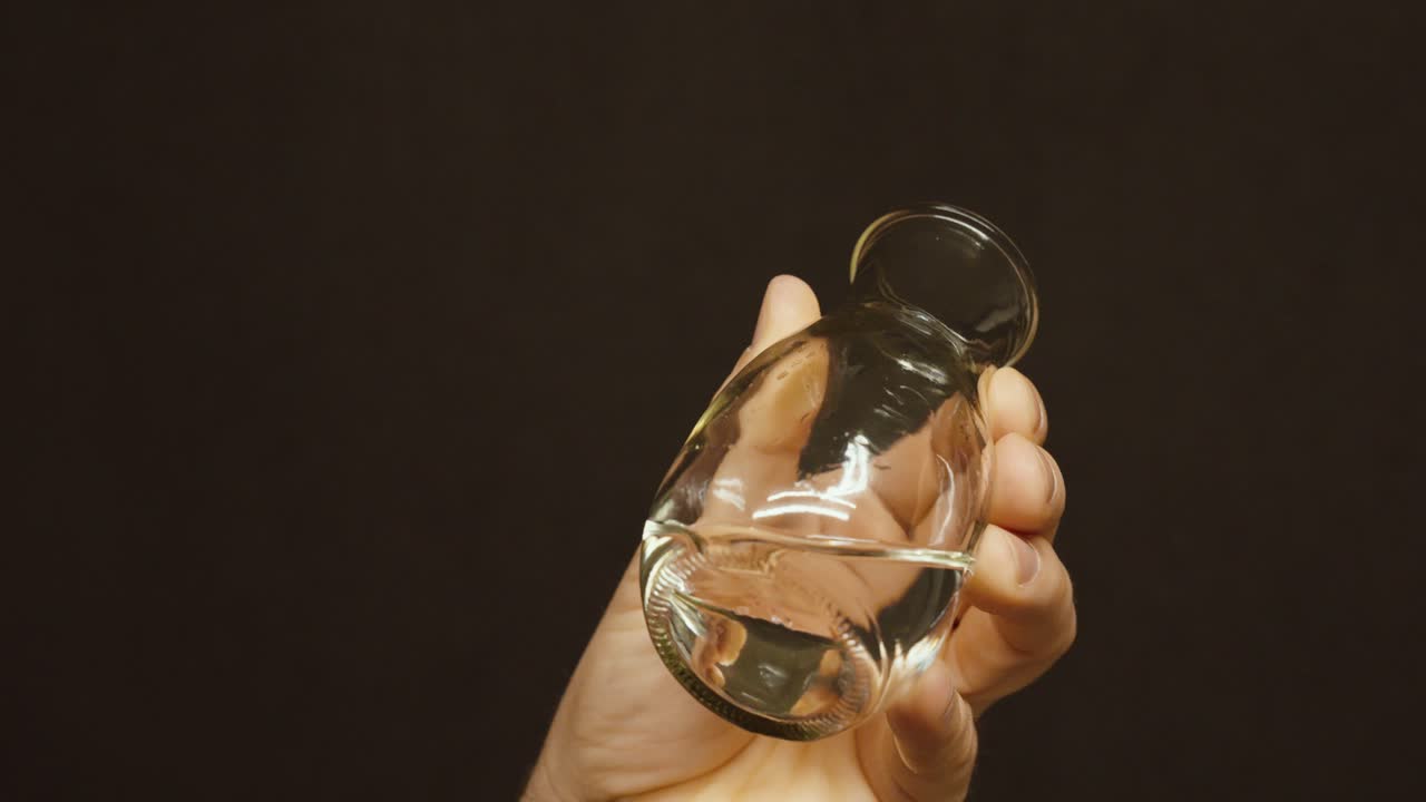 Primo piano di uno scienziato che tiene una fiaschetta di vetro con un campione di acqua limpida. Concetto di ricerca di laboratorio, test di qualità dell'acqua, scienze ambientali e analisi dell'acqua potabile pulita