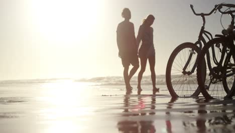 Couple-walking-together-on-shore-at-beach