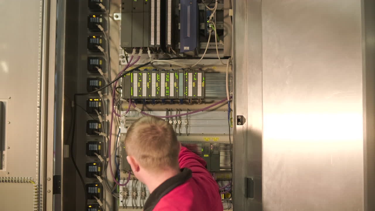 Engineer Inspecting Industrial Electrical Control Panel with Tablet