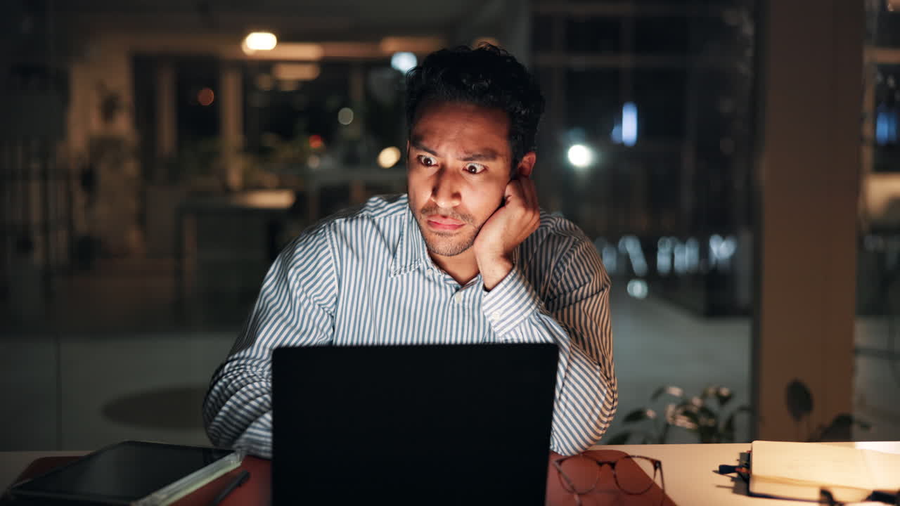 Stressed Man Working Late on Laptop in Dark Office