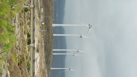 vertical view of spinning wind turbines on cloudy moody day