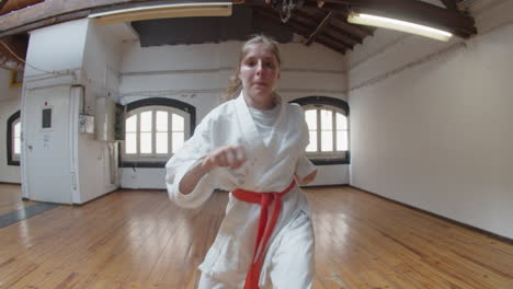 front view of focused girl punching and kicking in gym