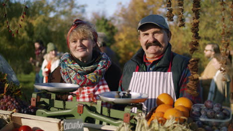 happy elderly couple of farmers selling products happy elderly couple of farmers standing near fresh fruits and vegetables looking at camera smiling shopping at local farmers market outdoors vegetarian organic and healthy food agriculture