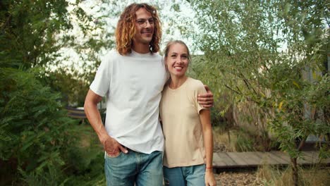 una chica con su novio rizado en una camiseta blanca están caminando y hablando solos entre sí en la casa de campo