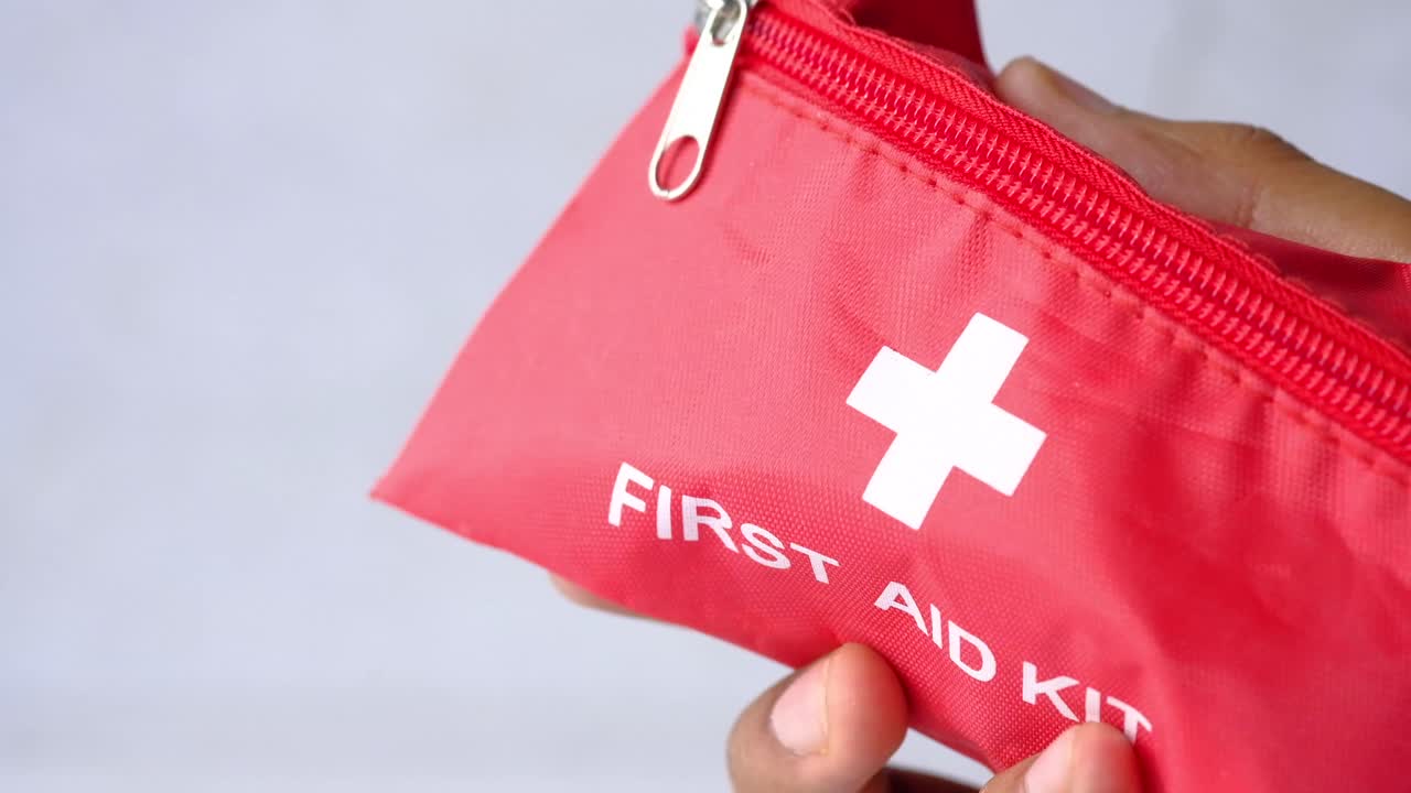 Hand holding a red first aid kit