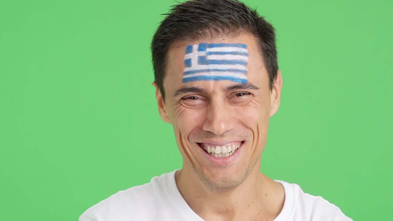 Man with a greek flag painted on the face smiling