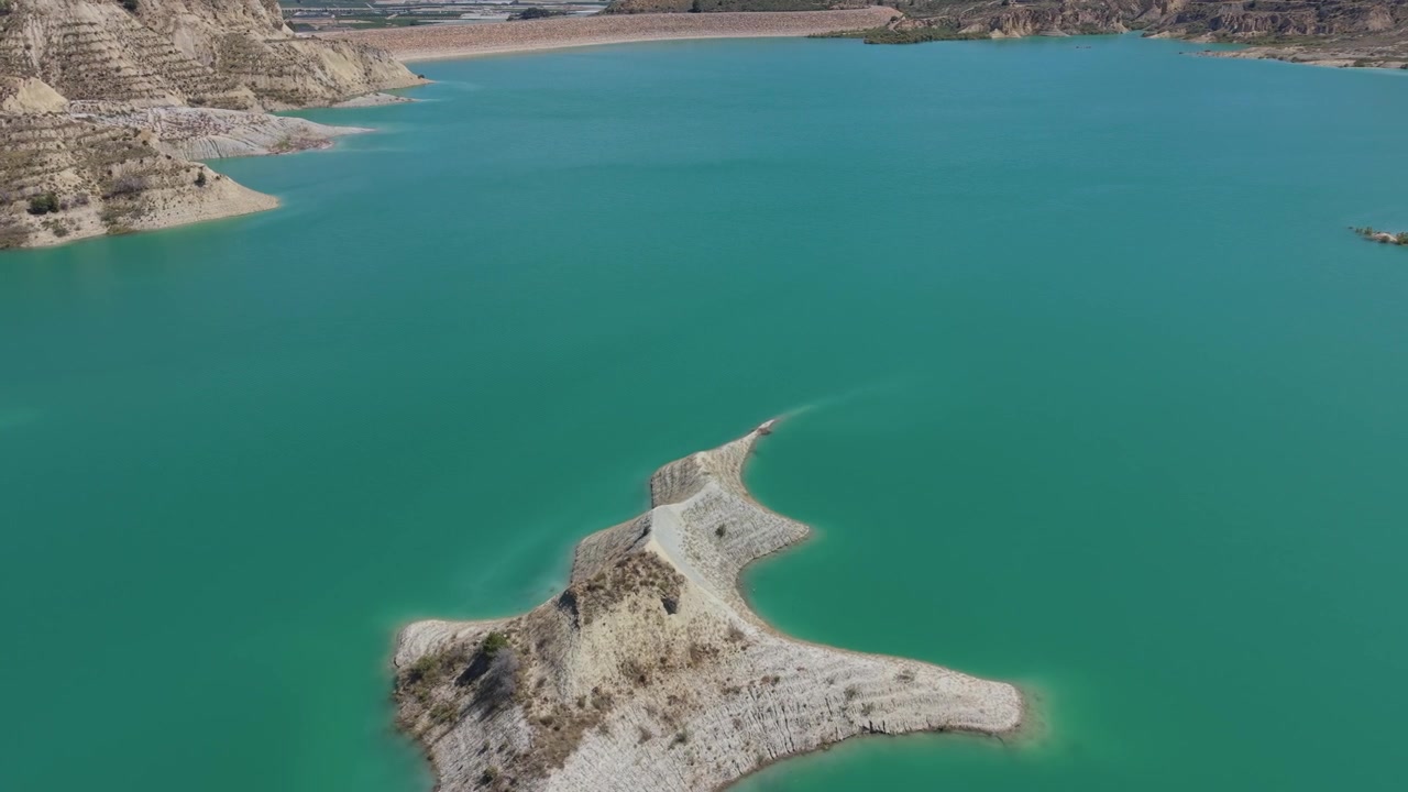 Vista aerea con drone di una penisola rocciosa circondata da acque turchesi nel bacino idrico di Embalse de Algeciras, Murcia, Spagna, che mostra un suggestivo paesaggio arido