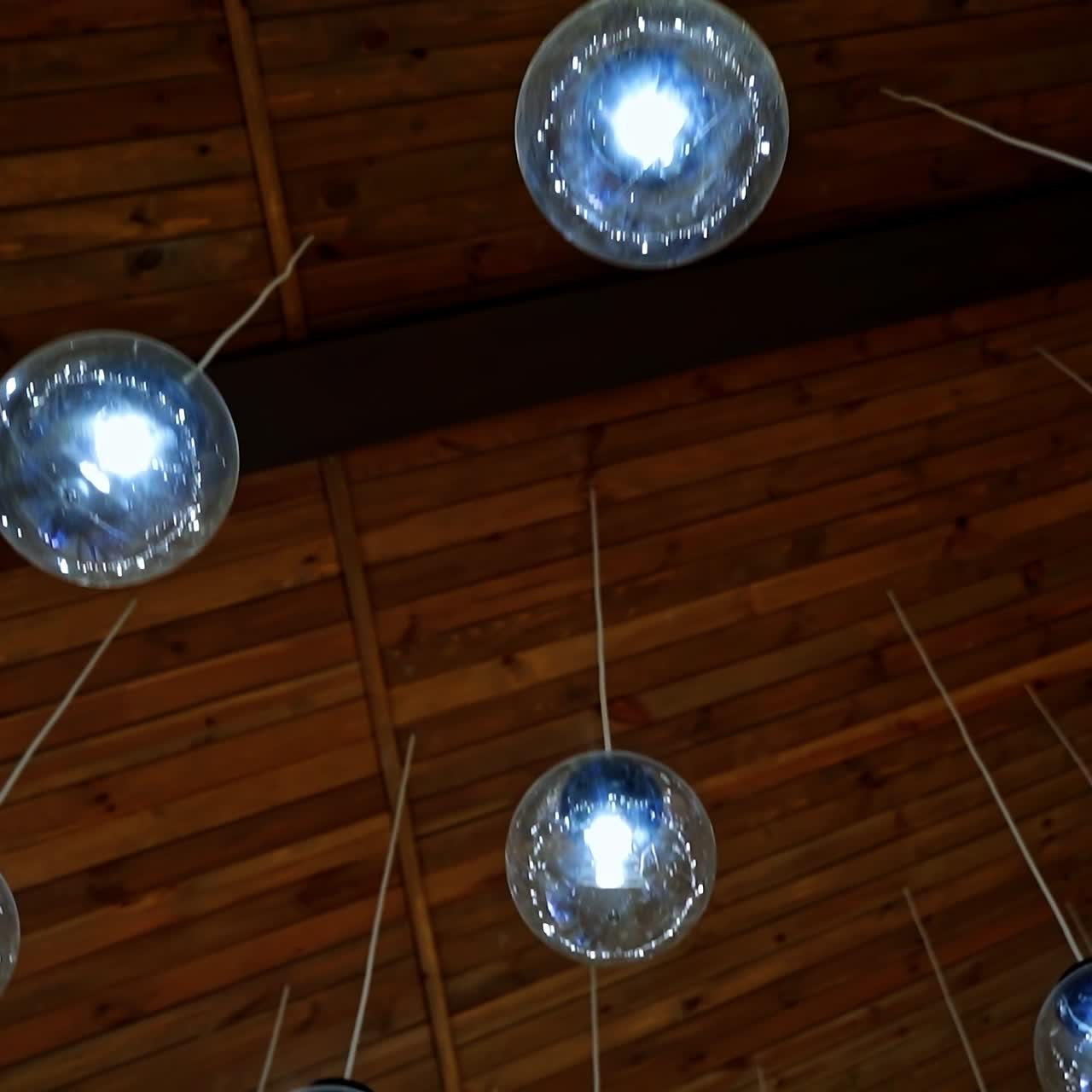 Modern ceiling lighting. Brown background with beautiful round glass ball lamps hanging on white wires. Luxury design of the room.