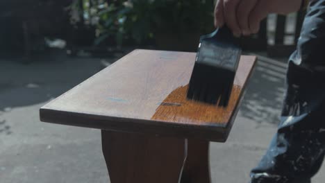 brushing varnish on teak timber stool outdoor 4k