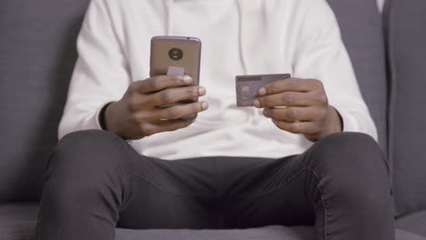 hands of young man typing credit card information on phone