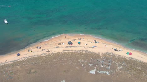 breathtaking drone view of tripoli's rabbit island. crystal waters, summer swimmers, and traditional boats create a mediterranean paradise. 4k resolution