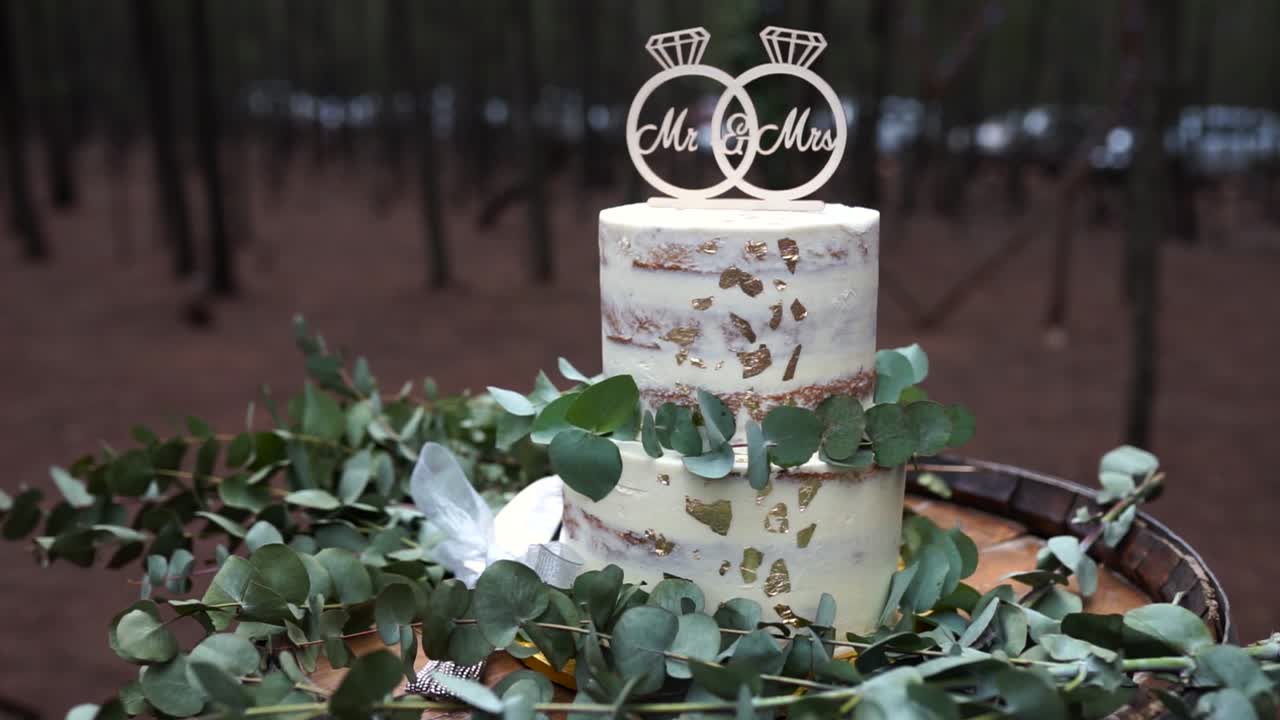 Plano médio de um bolo de casamento sobre um barril com folhas