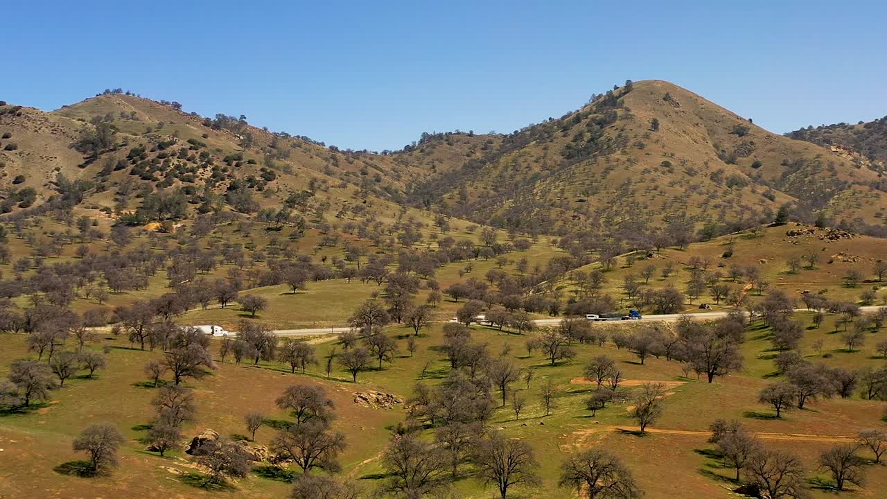 A highway transverses the foothills of the Tehachapi Mountain range - aerial parallax effect with trippy motion
