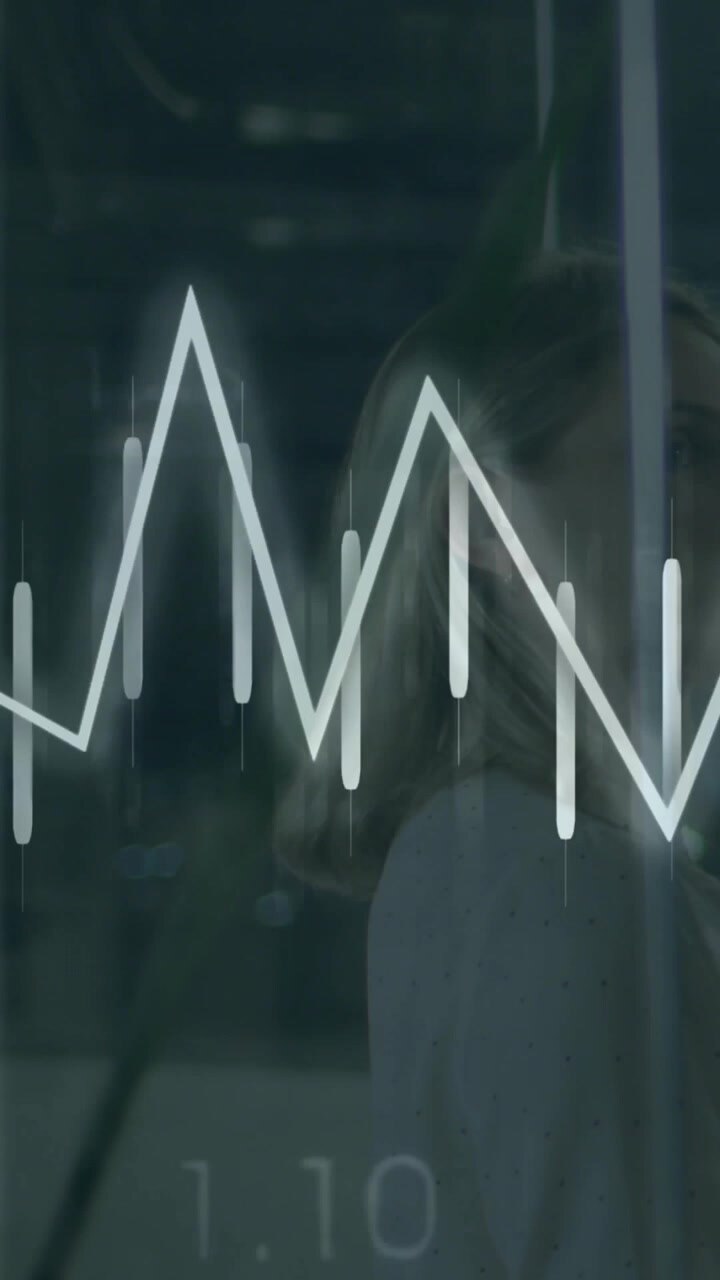 Vertical video: Tech woman behind glass tucking hair as overlay pulsing and animating graphs