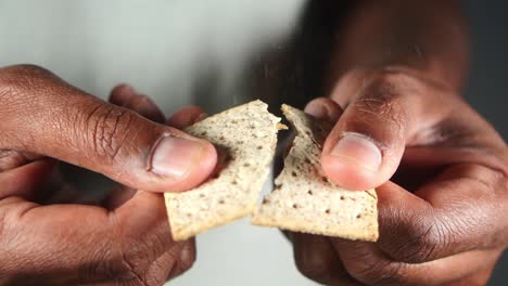 person holding and breaking a crackers