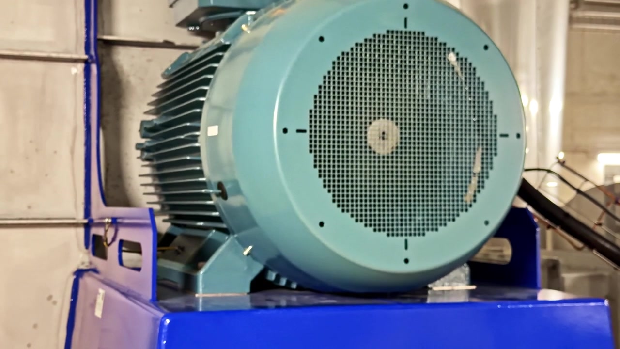 Detail průmyslového elektromotoru namontovaného na modré základně