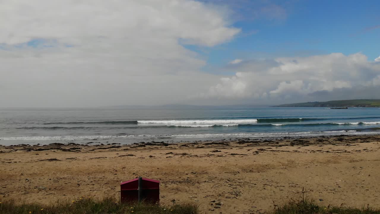 imágenes de drones de un vuelo directo desde dunas cubiertas de hierba sobre una playa de arena hasta el océano azul en un día soleado