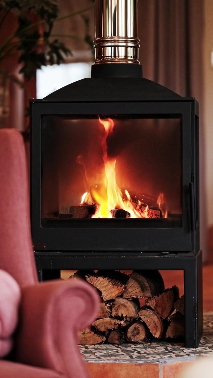 Vertical shot of a cozy wood burner stove with a fire burning in a living room