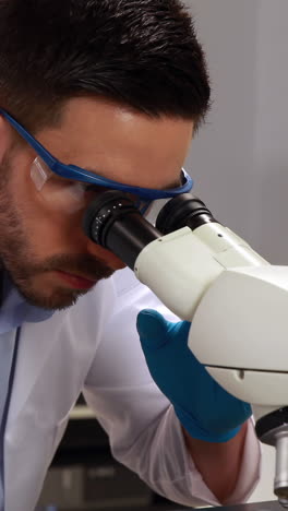 joven científico mirando a través del microscopio en el laboratorio