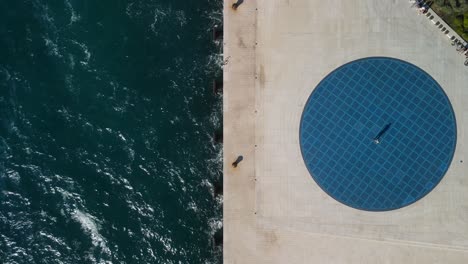 woman walking on a beautiful blue circle floor, seaside promenade