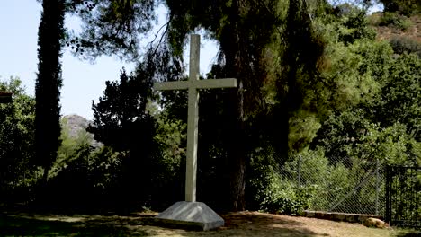 a stunning cross rises from the ground surrounded by lush trees and vibrant greenery in a tranquil valley, bathed in warm sunlight, evoking a sense of peace and reflection