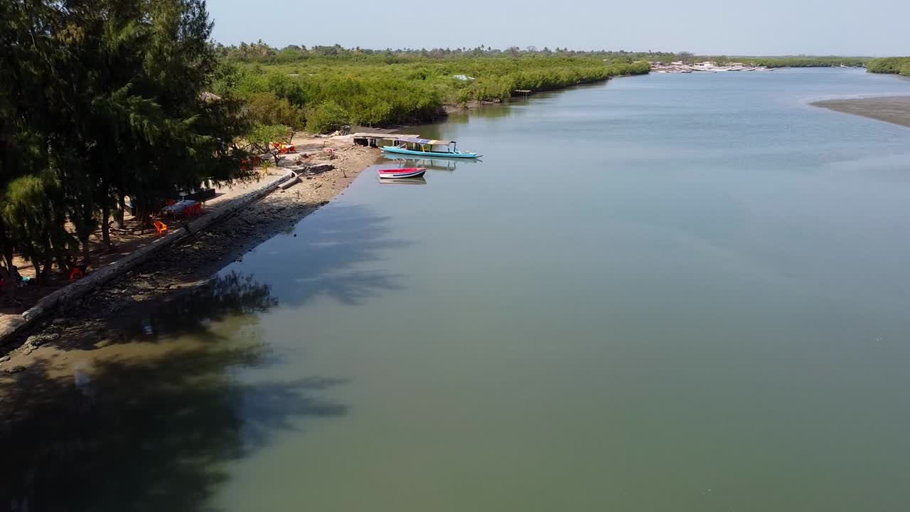 Descending aerial drone shot from the River Gambia with canoes in water for travelers and tourists on a sunny day