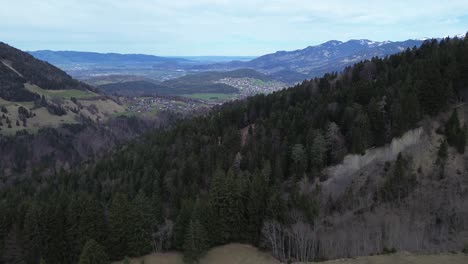 Drone-fly-in-the-mountains-of-Austria-above-pine-forest-with-view-over-valley