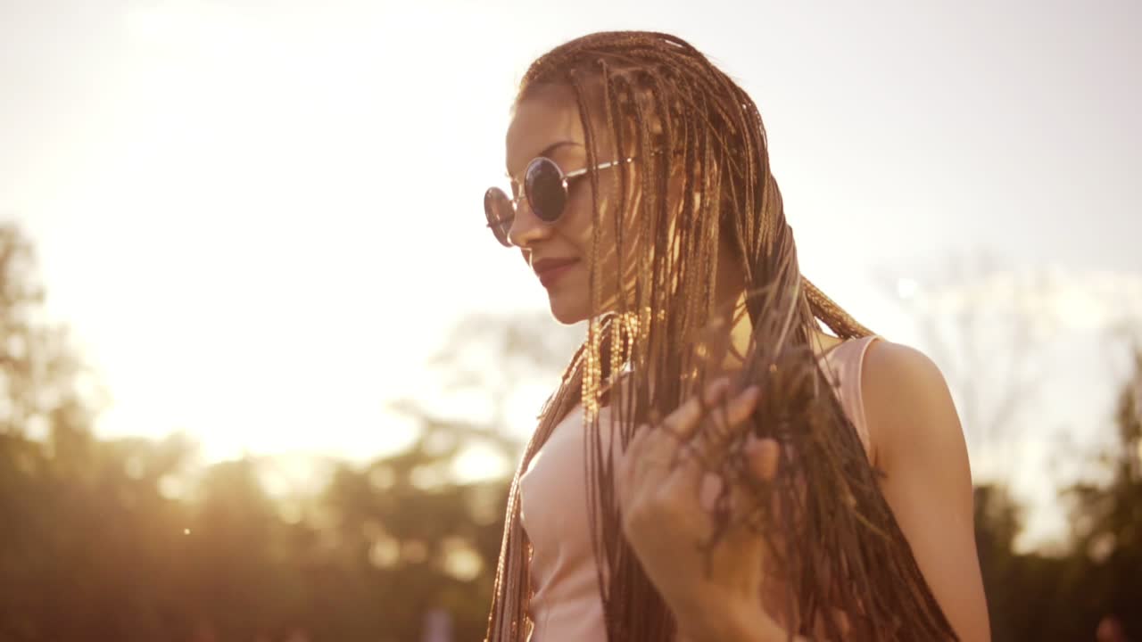una mujer hermosa con vaqueros y gafas de sol escuchando música y bailando.