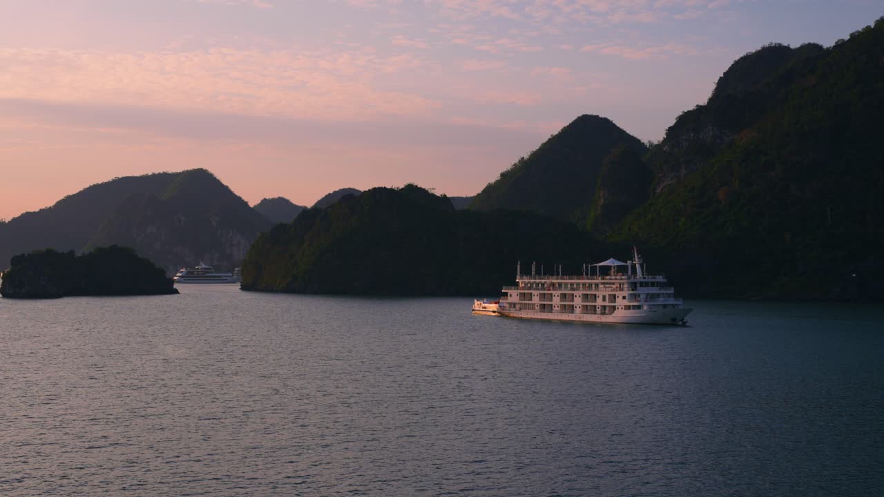 Tour Ship Cruising Along Limestone Karst Mountians at Halong Bay during sunrise, Vietnam
