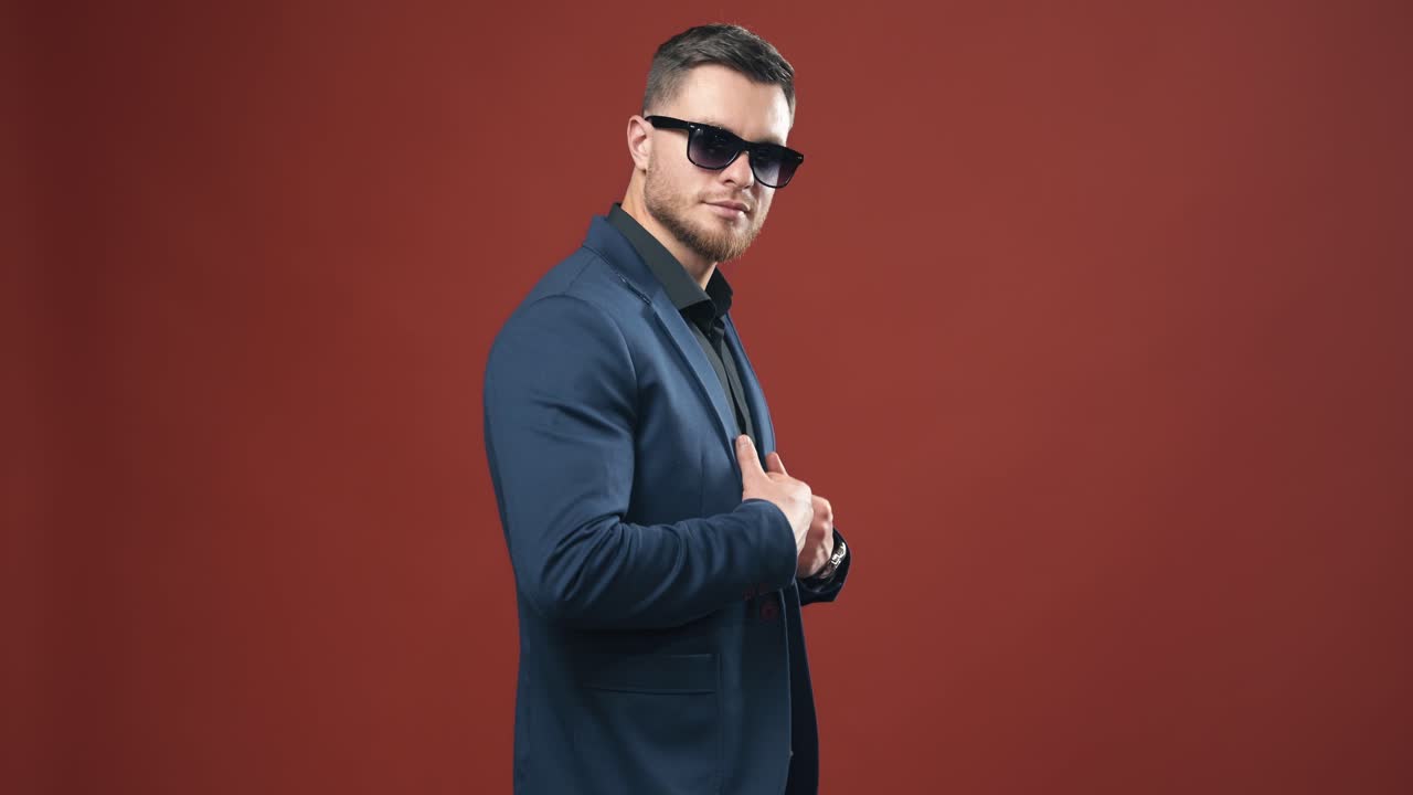 Side view of entrepreneur in glasses. Handsome bearded man in stylish costume isolated in studio. Young businessman in black glasses indoors.