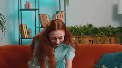 happy redhead woman at home use smartphone typing browsing wow yes found out great big win celebrate