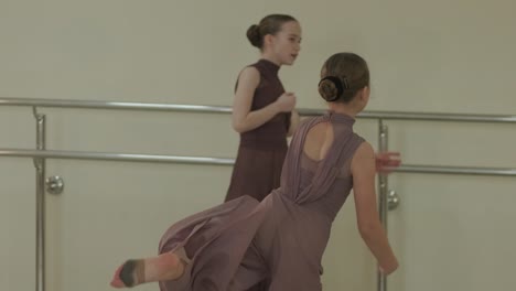 a group of young ballet students in black dancewear practicing positions in a spacious ballet studio with wooden flooring and wall-mounted barres. focused expressions and synchronized movements.