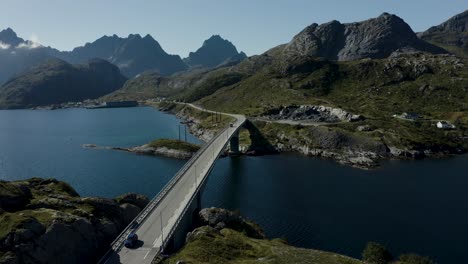 Aerial-drone-shot-of-bridge-across-the-ocean-with-mountains-in-the-background