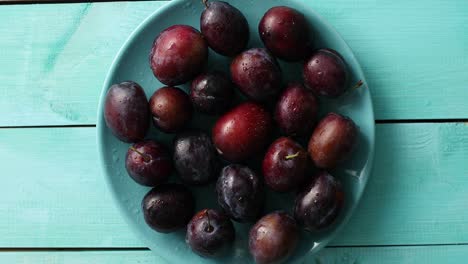 Wet-plums-on-blue-plate-on-table