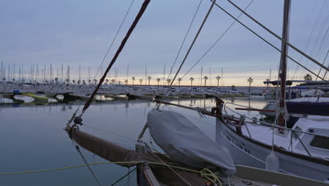 Time-lapse-port-docked-boats-moving-gently-in-wind,-dusky-gray-sky-at-pier