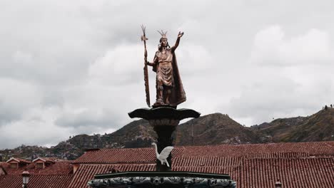 goldene atahualpa-statue auf dem hauptplatz von cuzco mit dächern und bergen - zeitraffer