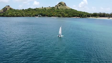 a aerial view of a small sailboat in the blue of the caribbean waters on a sunny day